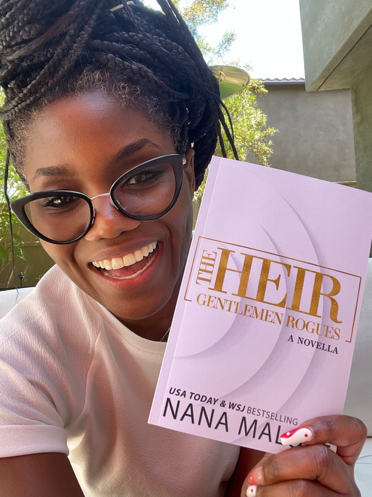 Nana Malone holding a paperback copy of her novella The Heir